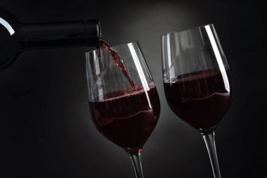Lezzetli kırmızı şarap cam koyu arka plan üzerinde içine dökme