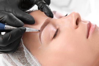 Young woman undergoing eyebrow correction procedure in salon clipart