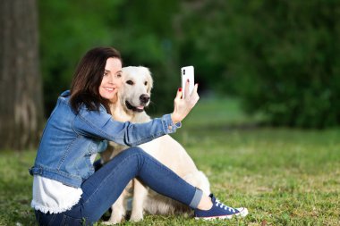 Genç kadın selfie köpeğini birlikte parkta alıyor. Evde beslenen hayvan kaygı