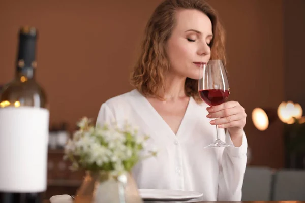 Woman with glass of wine at table in restaurant