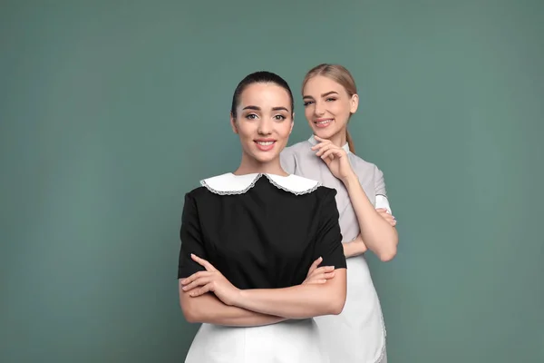 Portrait of young chambermaids on color background