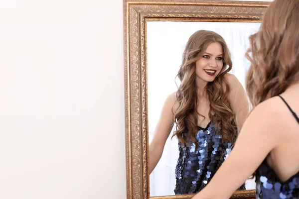 Young beautiful woman near mirror in makeup room