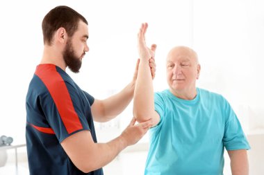 Klinikte kıdemli bir hastayla çalışan genç bir fizyoterapist.