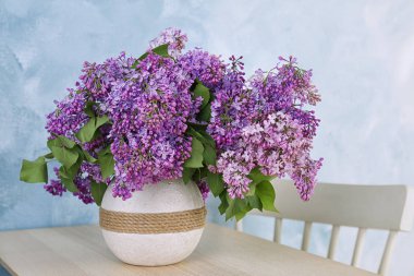 Vazo ile güzel çiçek açması leylak rengi arka plan karşı masada. Bahar çiçekleri