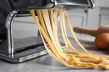 Mutfak masasında hamuru olan makarna makinesi.