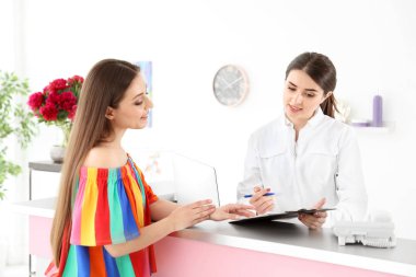 İstemci ile güzellik salonu masasında çalışan genç resepsiyonist