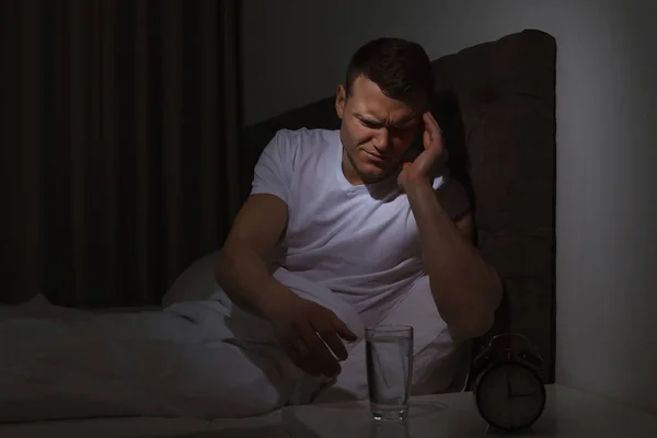 Young man with terrible headache want to take pill at night