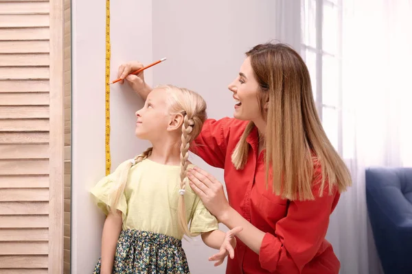 Mujer Joven Midiendo Altura Hija Casa —  Fotos de Stock