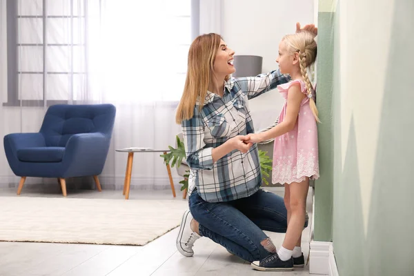 Mujer Joven Midiendo Altura Hija Casa —  Fotos de Stock