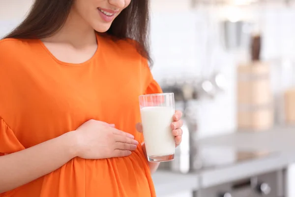 美しい妊娠中の女性は台所で牛乳を飲む — ストック写真