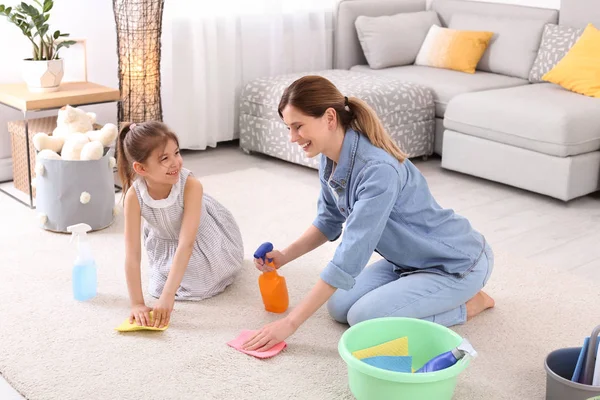 家庭主妇与女儿清洁地毯在房间里一起 — 图库照片
