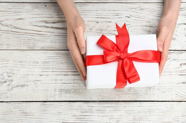 Güzel hediye kutusu ahşap arka plan, üstten görünüm üzerinde tutan genç kadın