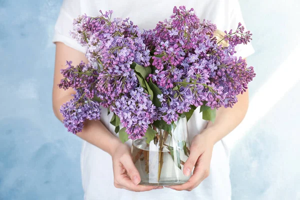 背景色の美しい開花ライラックと花瓶を保持している若い女性 春の花 — ストック写真