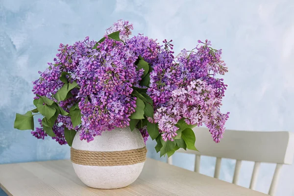 Vazo ile güzel çiçek açması leylak rengi arka plan karşı masada. Bahar çiçekleri