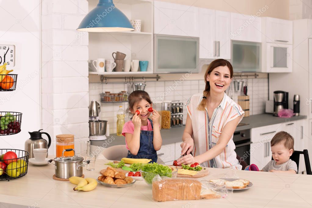 Housewife preparing dinner with her children on kitchen