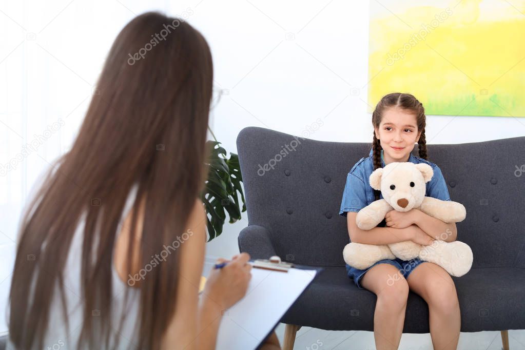 Child psychologist working with little girl in office