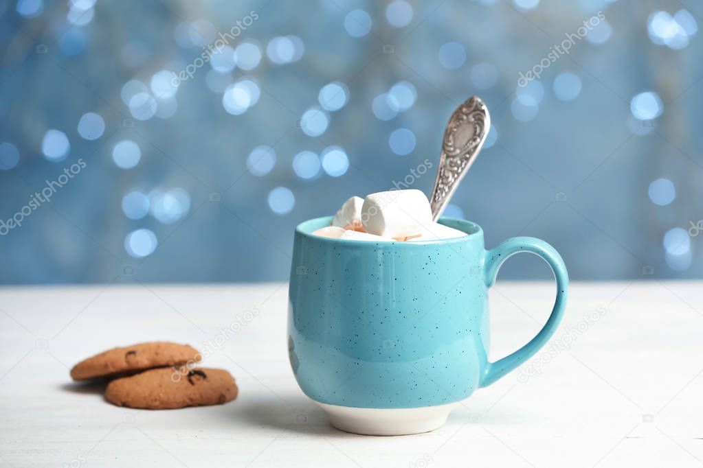 Cup with delicious hot cocoa drink with marshmallows on table