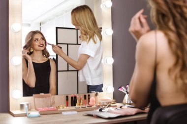 Profesyonel makyöz müşteriyle soyunma odasında çalışıyor.