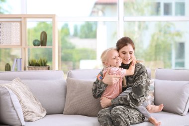 Küçük kızı evde kanepe ile askeri üniformalı kadın
