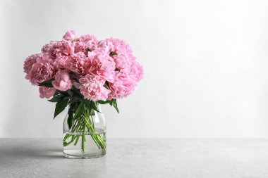 Masanın üzerinde açık arkaplanda güzel şakayık çiçekleri olan vazo.