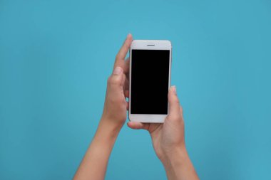 Cep telefonu ile boş perde renk arka plan üzerinde elinde tutan genç kadın