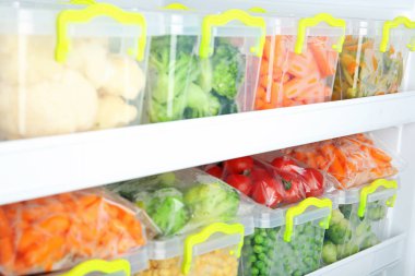 Containers with deep frozen vegetables in refrigerator clipart
