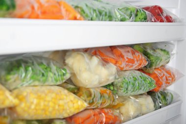 Plastic bags with deep frozen vegetables in refrigerator clipart