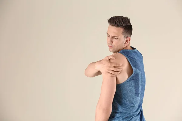 Mann Sportkleidung Leidet Schulterschmerzen Vor Hellem Hintergrund — Stockfoto
