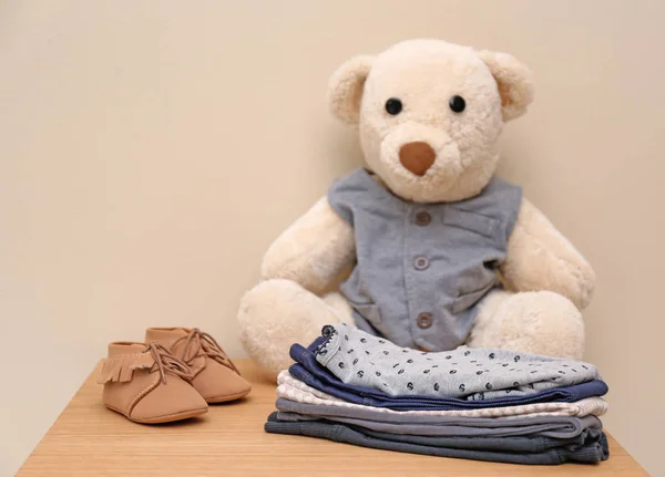 泰迪熊和时尚儿童服装在桌子上反对光背景 — 图库照片