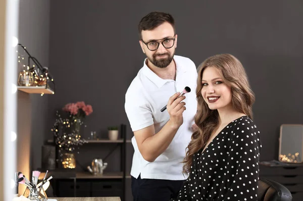 Professional makeup artist working with client in dressing room