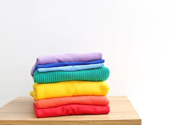 Stack of rainbow clothes on table against white background