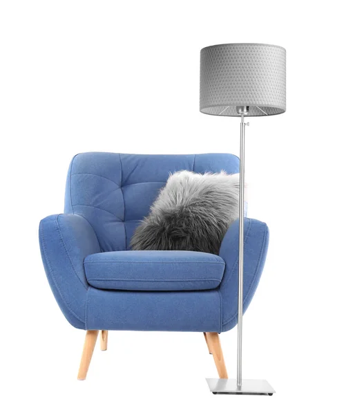 Comfortable armchair with pillow and lamp on white background