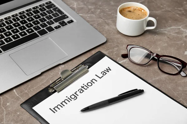 移民法の言葉でクリップボードとクローズ アップのテーブルの上のノート パソコン — ストック写真