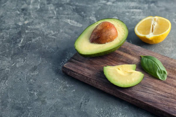 Houten Plank Met Gesneden Avocado Citroen Grijze Achtergrond — Stockfoto