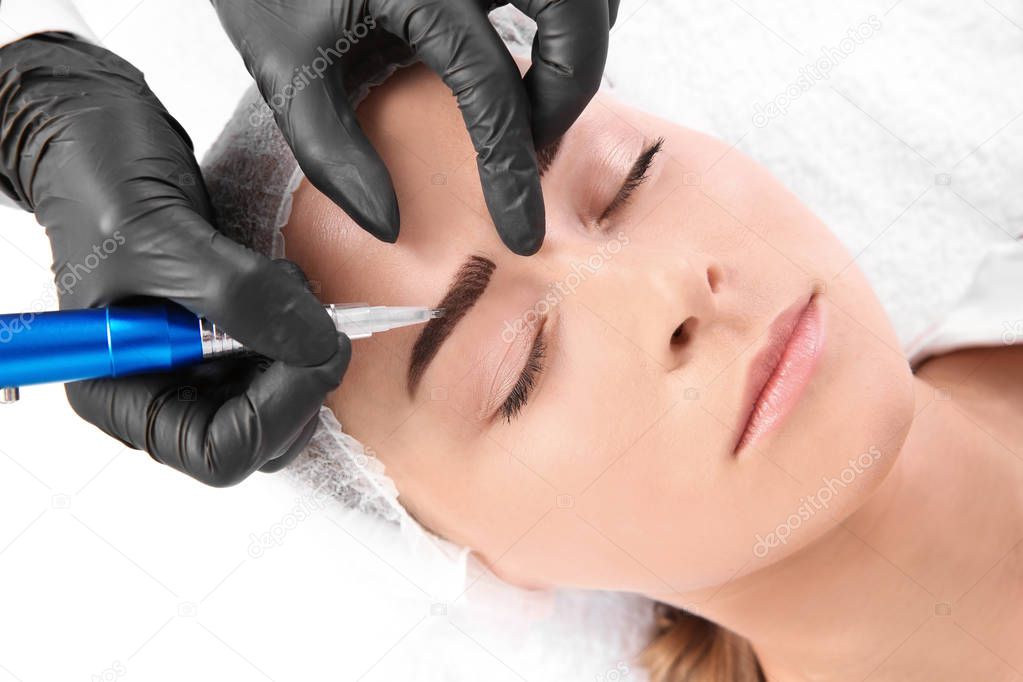 Young woman undergoing eyebrow correction procedure in salon