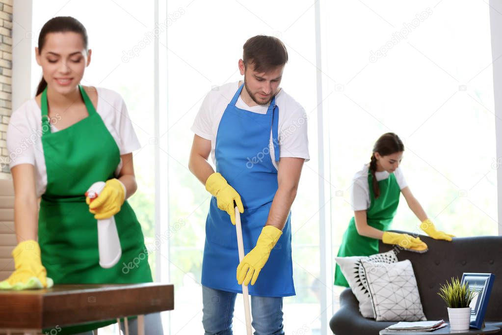 Team of professional janitors in uniform cleaning office