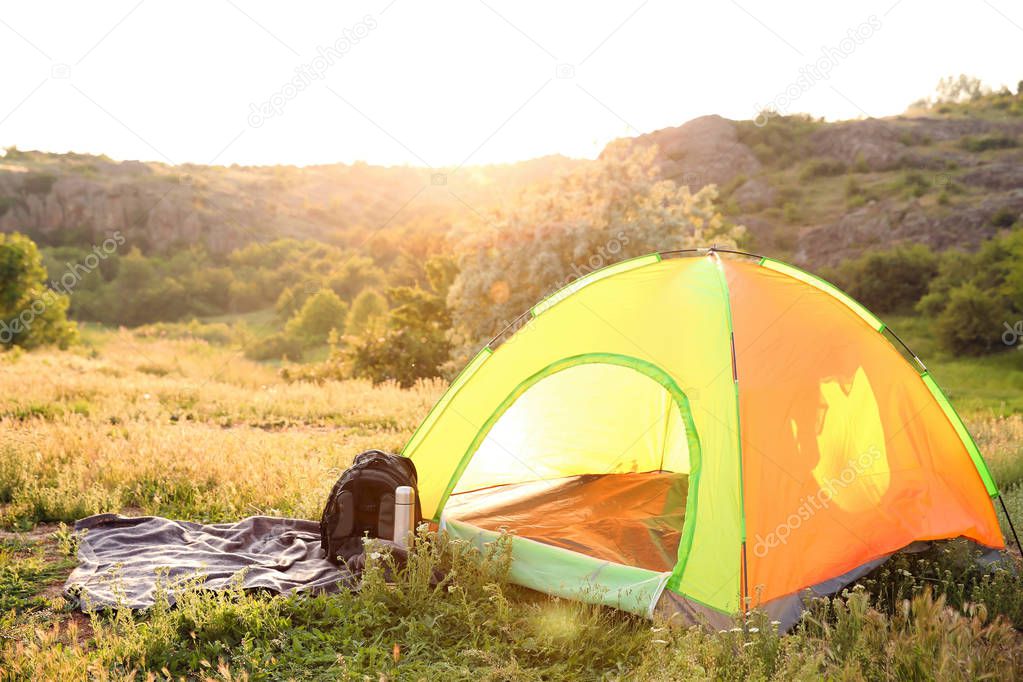 Camping gear and tourist tent in wilderness on sunny day