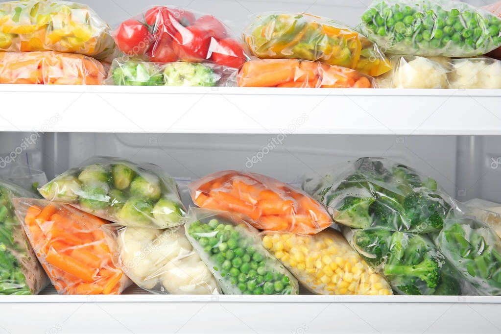 Plastic bags with deep frozen vegetables in refrigerator