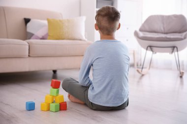 Evde katta oturan küpleri ile yalnız küçük çocuk. Otizm kavramı