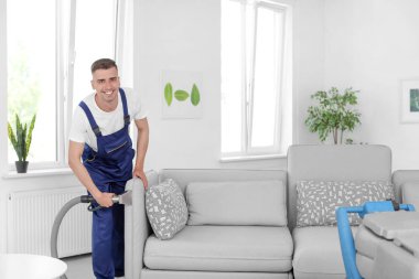 Kuru temizleme işçisi kanepedeki kiri temizliyor.