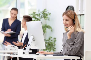 Ofiste masasında kulaklık ile kadın resepsiyonist