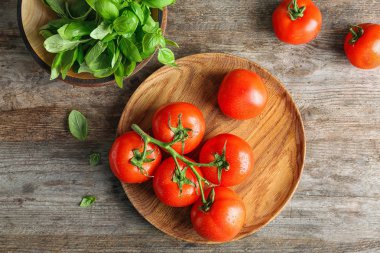 Olgun domates ve fesleğen ahşap arka plan üzerinde düz yatıyordu kompozisyonu