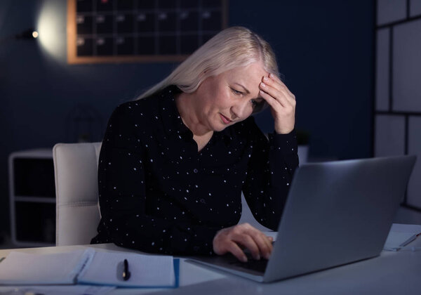 Overworked mature woman with headache in office