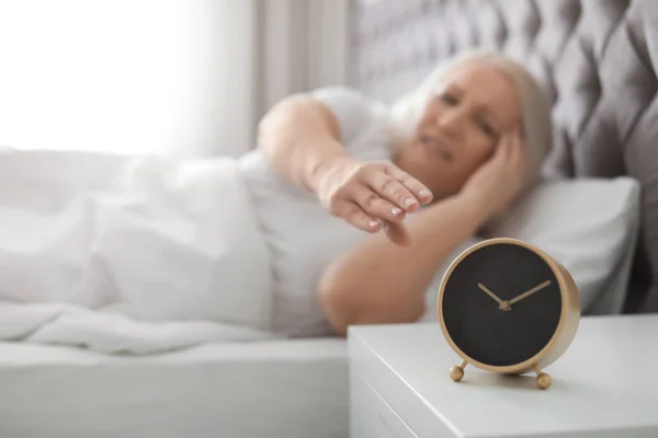 目覚まし時計をオフにしようとすると ひどい頭痛と成熟した女性 — ストック写真