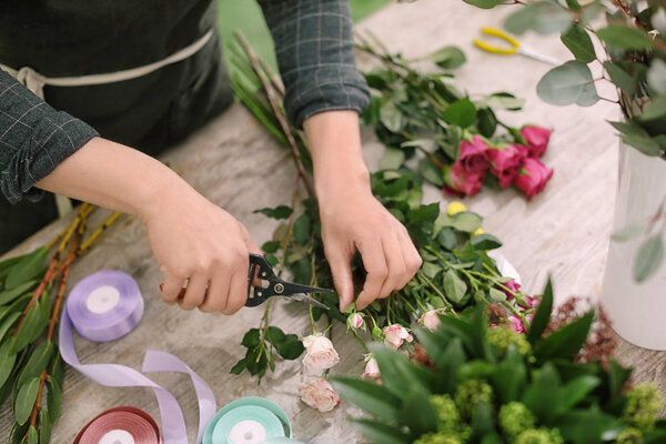 Male florist making beautiful bouquet in flower shop, closeup