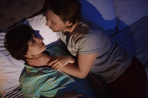 Young couple in love on bed at night time