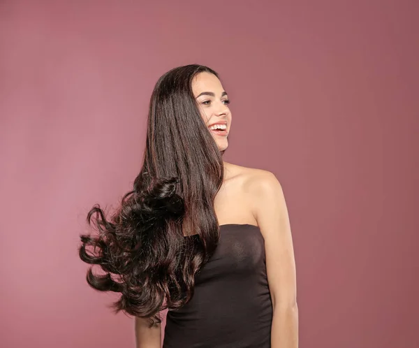 色背景にゴージャスな巻き毛の美しいモデルの肖像 — ストック写真
