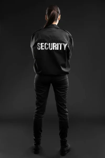 Female security guard in uniform on dark background