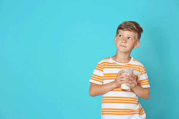 可爱的小男孩与玻璃牛奶在颜色背景 — 图库照片