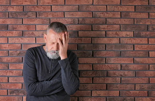 レンガの壁の近くのうつ病の状態で年配の男性 — ストック写真